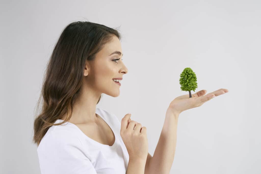 Mulher segurando uma pequena árvore nas mãos, representando o ROI da Sustentabilidade e o crescimento verde das empresas